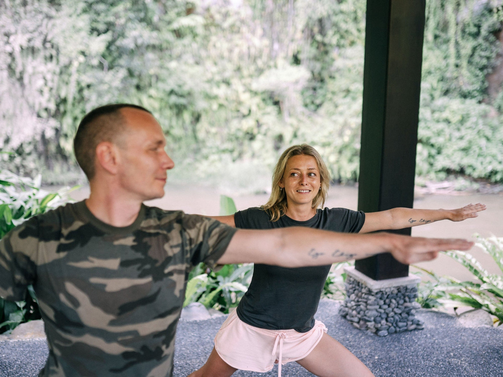 Zwei Personen machen gemeinsam Yoga in einem offenen Studio auf Bali
