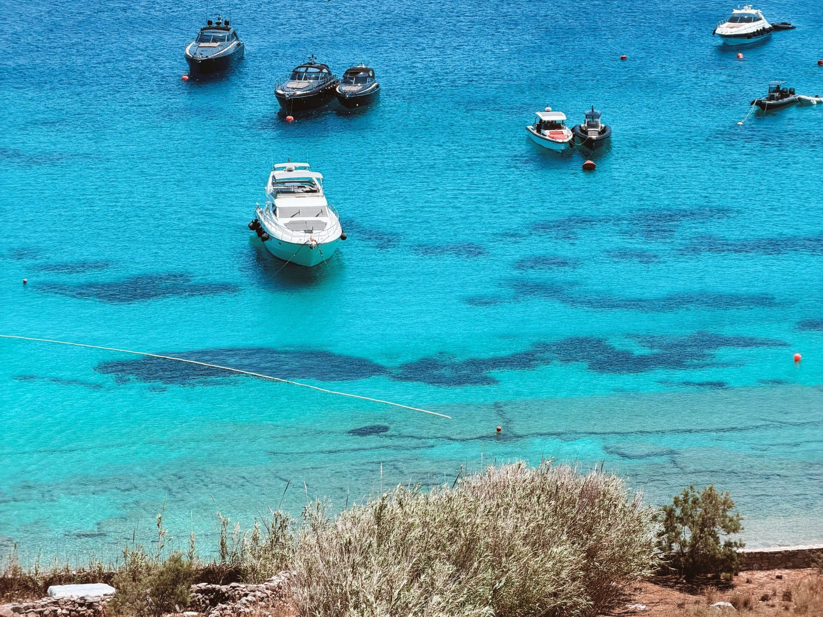 Yachten und Boote auf türkisblauem Meer vor Mykonos