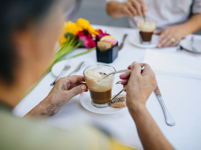 Zwei Personen trinken gemeinsam Kaffee an einem gedeckten Tisch